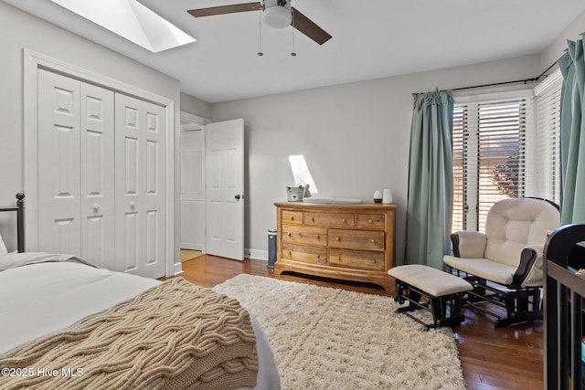 bedroom with hardwood / wood-style floors, ceiling fan, a skylight, and a closet