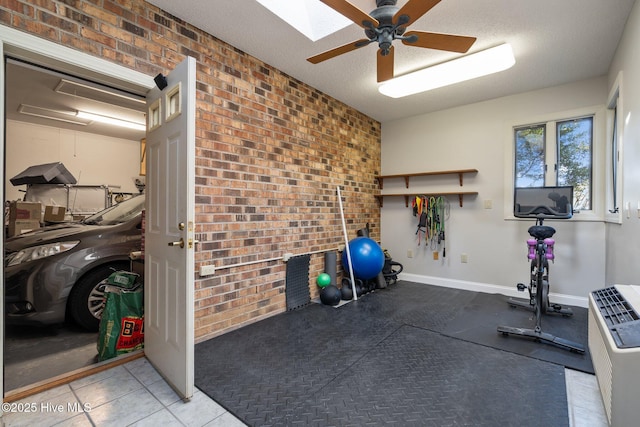 workout room with a textured ceiling, ceiling fan, and brick wall