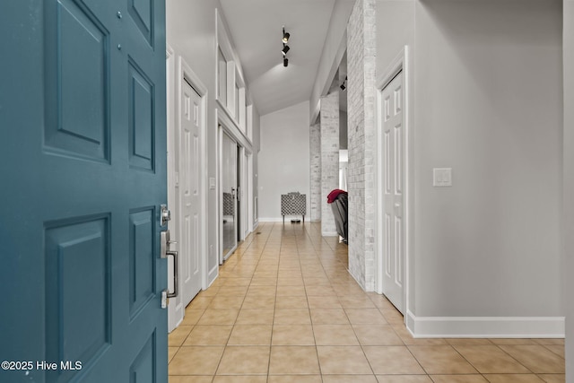 corridor featuring light tile patterned flooring and vaulted ceiling