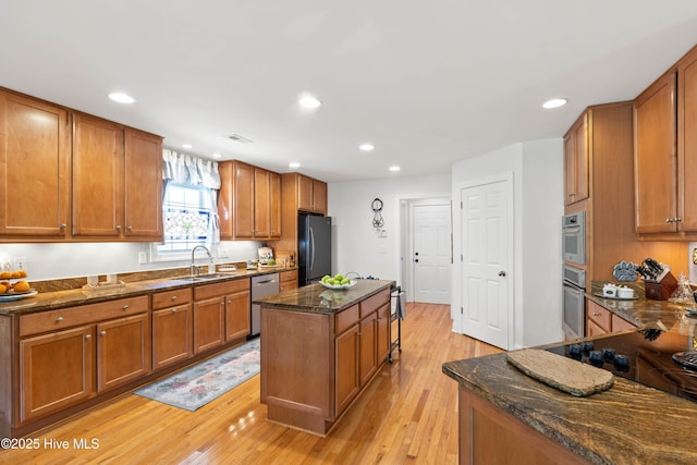 kitchen featuring sink, dark stone countertops, fridge, stainless steel dishwasher, and a kitchen island