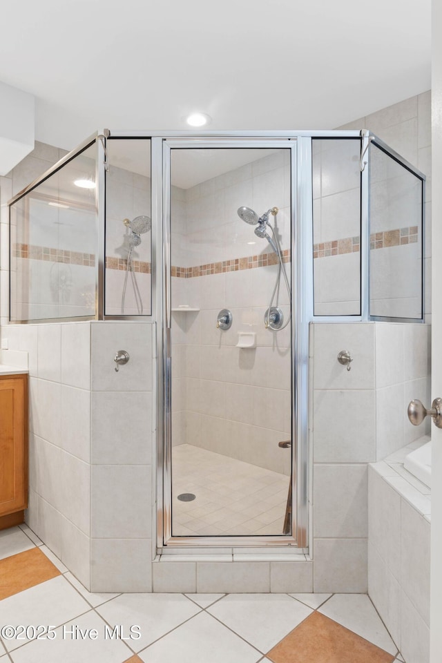 full bath featuring tile patterned flooring, a shower stall, vanity, and tiled tub