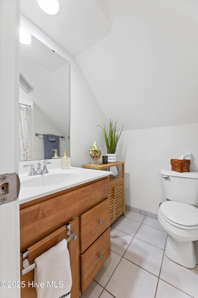 bathroom with tile patterned flooring, vanity, vaulted ceiling, and toilet