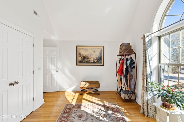 sitting room with vaulted ceiling, light wood-style flooring, visible vents, and baseboards