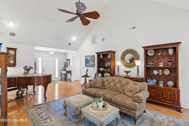 living room featuring ceiling fan, high vaulted ceiling, and light hardwood / wood-style flooring