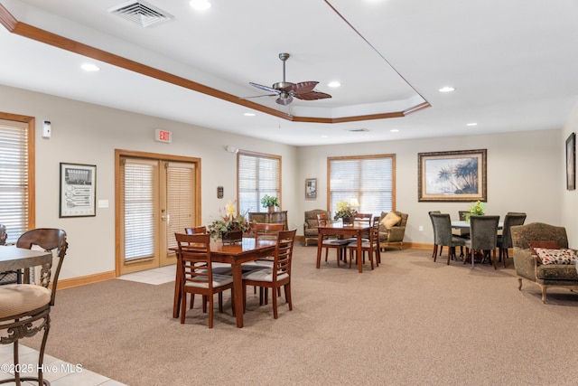 carpeted dining area featuring ceiling fan and a raised ceiling