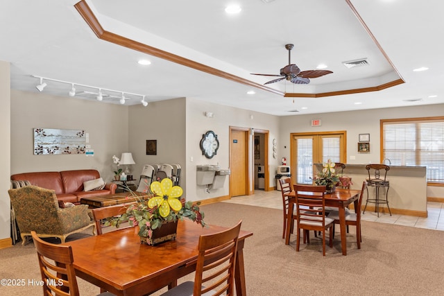 dining room with rail lighting, light colored carpet, a raised ceiling, and ceiling fan