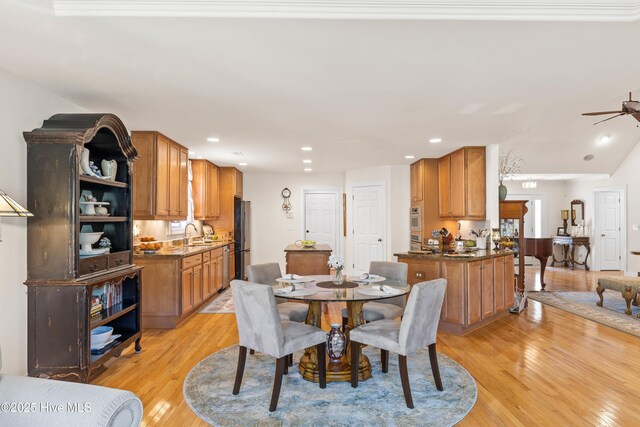 dining room with sink, ceiling fan, and light wood-type flooring