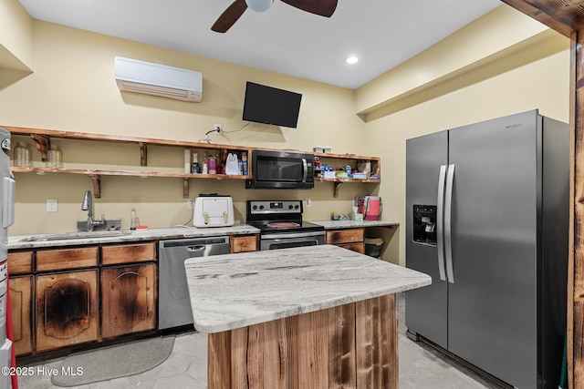 kitchen featuring appliances with stainless steel finishes, a wall unit AC, ceiling fan, sink, and a center island