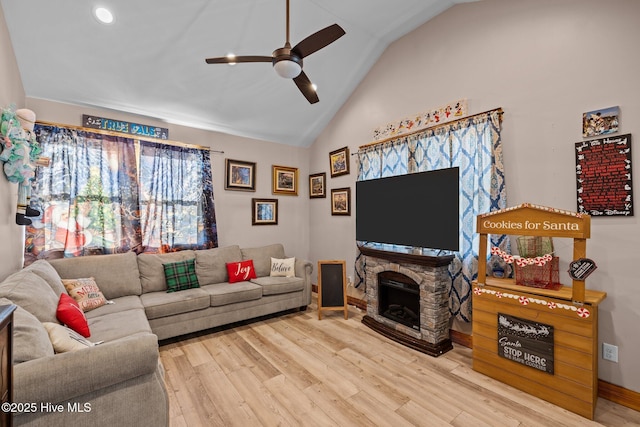 living room featuring ceiling fan, a stone fireplace, wood-type flooring, and lofted ceiling