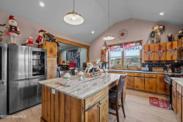 kitchen featuring backsplash, light hardwood / wood-style flooring, vaulted ceiling, a kitchen island, and stainless steel appliances