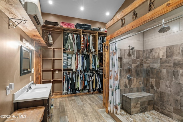 spacious closet with light hardwood / wood-style floors, vaulted ceiling, and sink