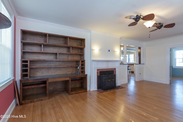 unfurnished living room featuring baseboards, built in shelves, light wood-type flooring, and crown molding