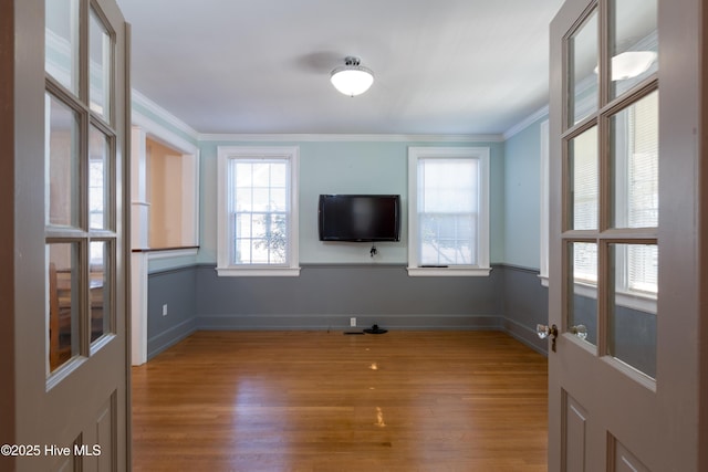 unfurnished living room with baseboards, light wood-type flooring, and crown molding