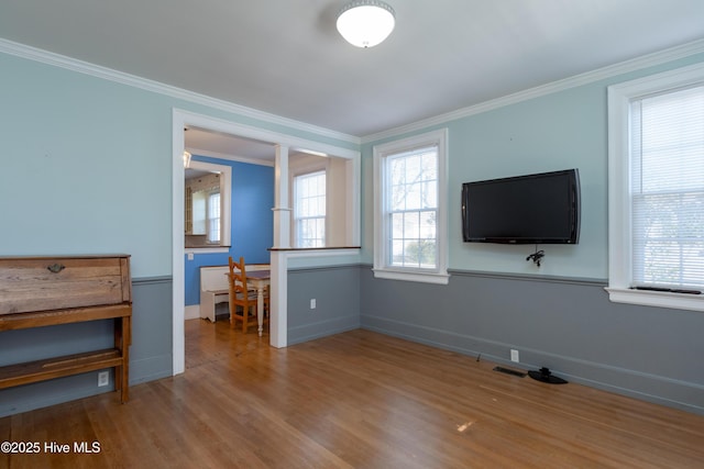 unfurnished living room featuring ornamental molding, baseboards, and wood finished floors