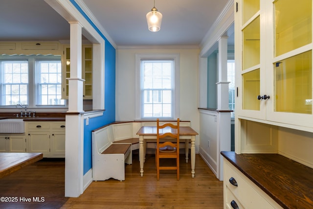 dining room with breakfast area, ornamental molding, baseboards, and wood finished floors