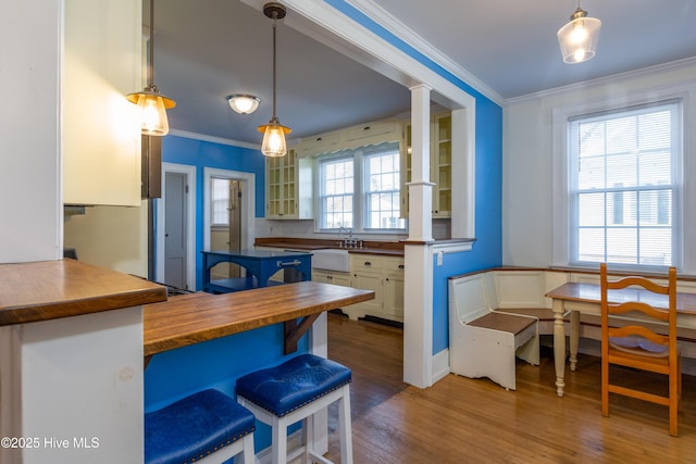 kitchen featuring glass insert cabinets, wood finished floors, crown molding, and wooden counters