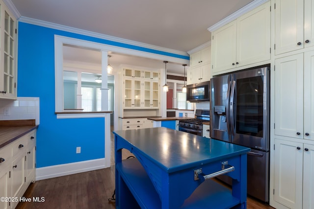 kitchen with stainless steel appliances, a center island, dark countertops, dark wood finished floors, and crown molding