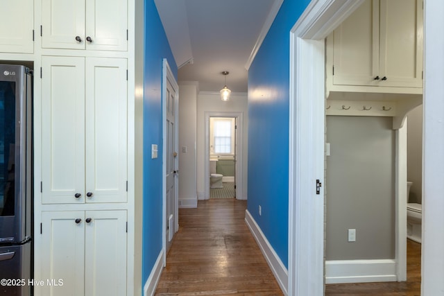 hall featuring baseboards, dark wood-style flooring, and crown molding