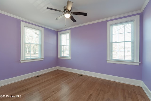 spare room with ornamental molding, light wood-type flooring, visible vents, and baseboards