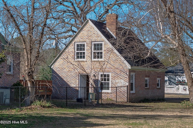 exterior space featuring a yard, brick siding, fence, and a chimney