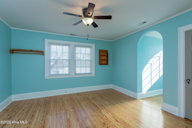 unfurnished room with baseboards, wood finished floors, visible vents, and crown molding