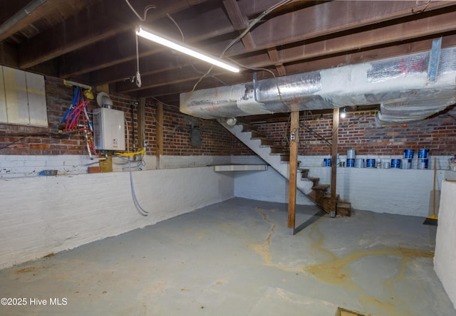 unfinished basement featuring brick wall, stairs, and tankless water heater