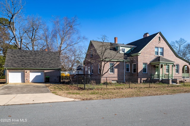 view of front of home with a fenced front yard, brick siding, driveway, and a chimney