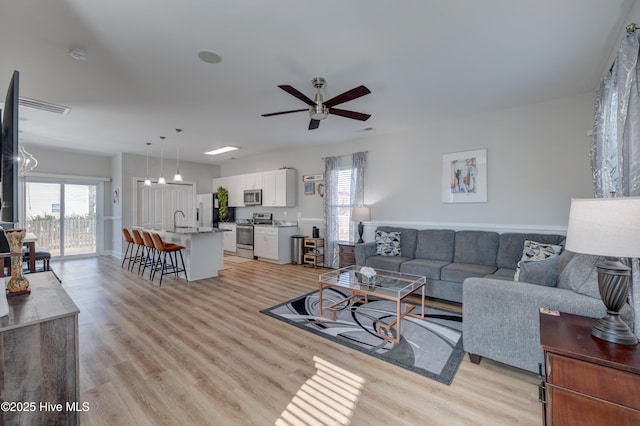 living room featuring ceiling fan, sink, and light hardwood / wood-style flooring