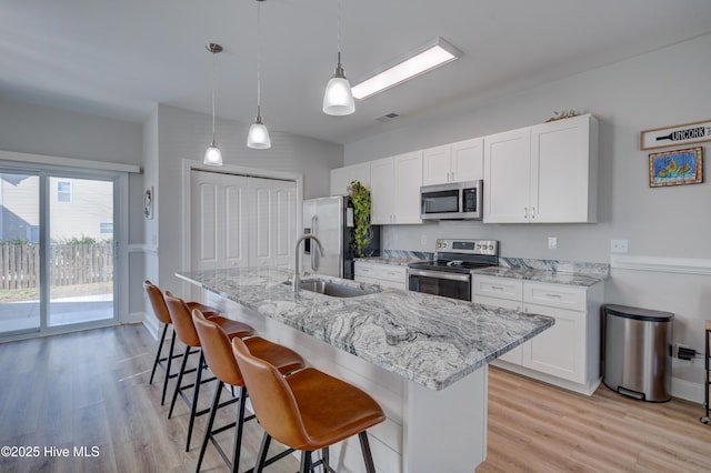 kitchen featuring pendant lighting, a kitchen breakfast bar, sink, white cabinetry, and stainless steel appliances