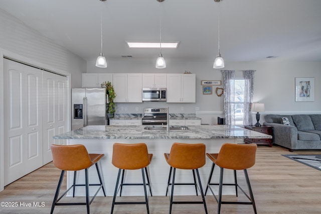 kitchen featuring white cabinets, appliances with stainless steel finishes, hanging light fixtures, and a large island