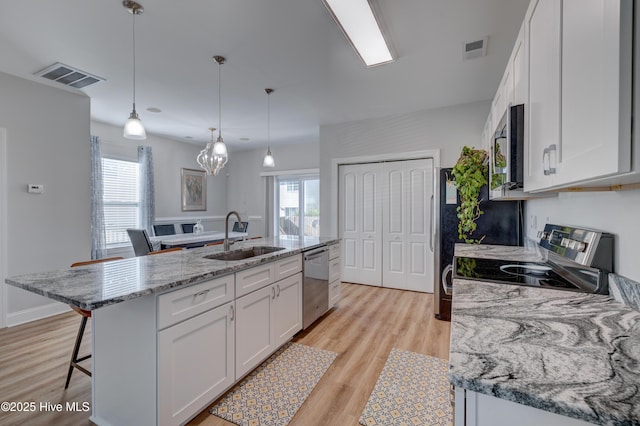 kitchen with white cabinets, a center island with sink, hanging light fixtures, sink, and appliances with stainless steel finishes