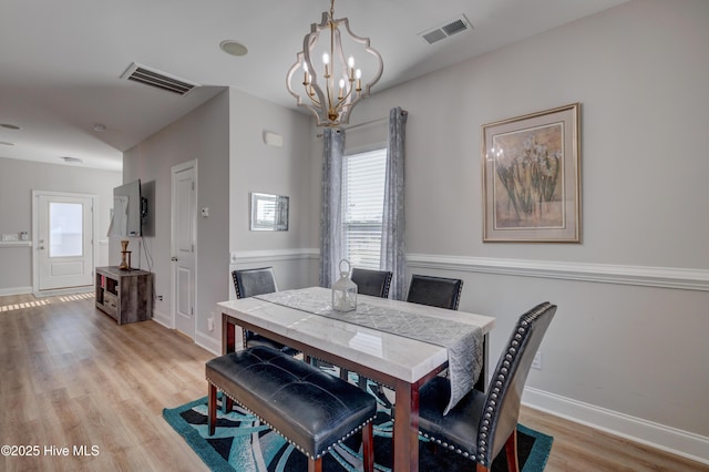 dining area featuring a notable chandelier and light wood-type flooring