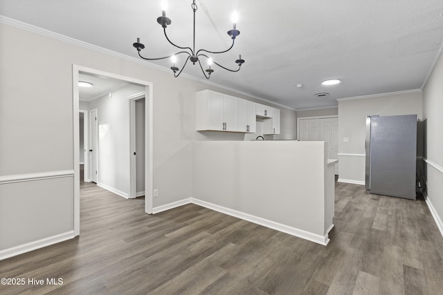 unfurnished dining area with a textured ceiling, dark hardwood / wood-style flooring, crown molding, and a chandelier