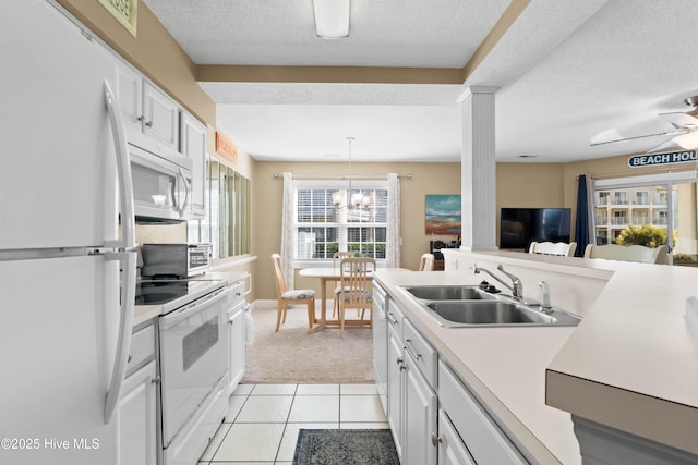 kitchen featuring white cabinetry, sink, white appliances, and decorative light fixtures