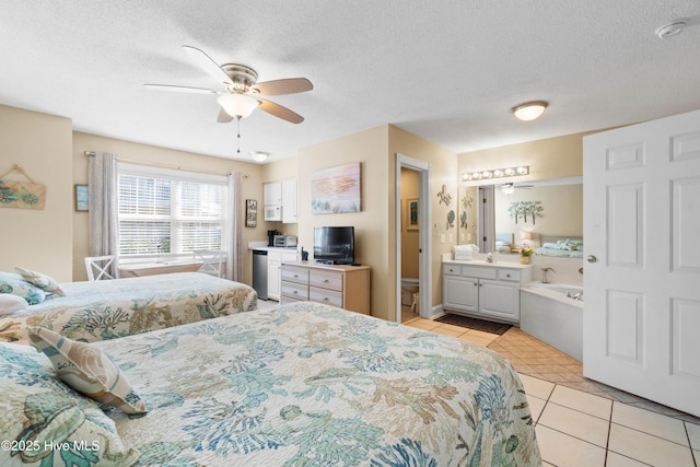 bedroom featuring ensuite bathroom, light tile patterned floors, ceiling fan, and a textured ceiling