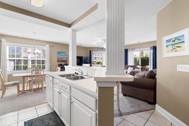 kitchen featuring decorative light fixtures, dishwasher, sink, a breakfast bar area, and white cabinets