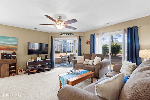 carpeted living room featuring ceiling fan and a textured ceiling