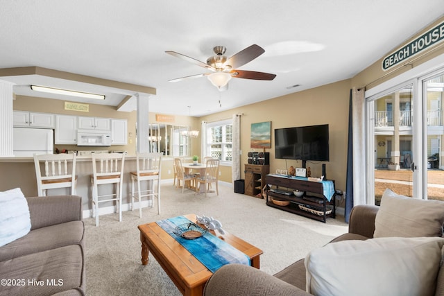 living room with light colored carpet and ceiling fan with notable chandelier