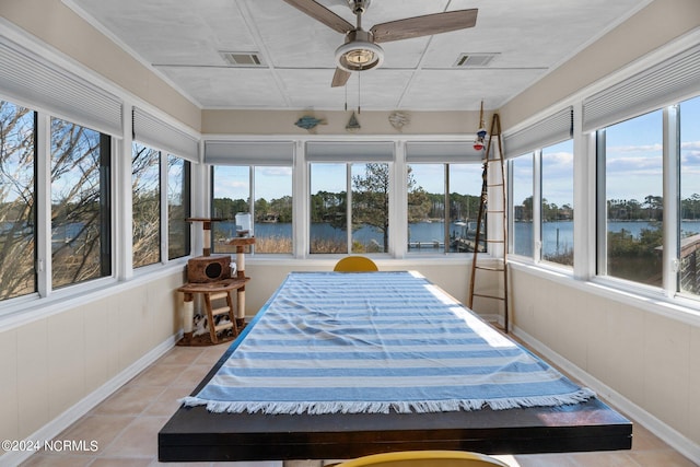 sunroom / solarium featuring ceiling fan and a water view