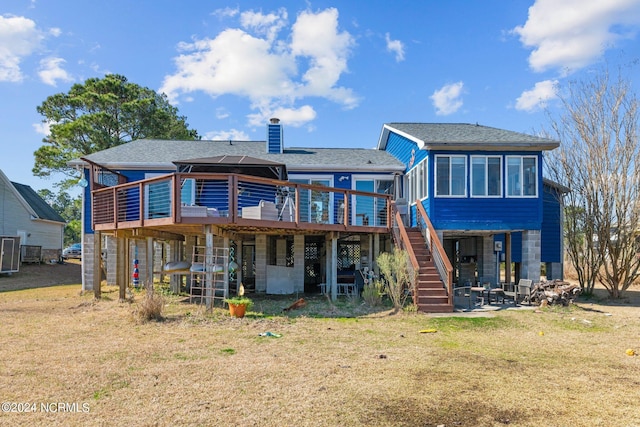 rear view of property featuring a lawn, a patio area, and a wooden deck