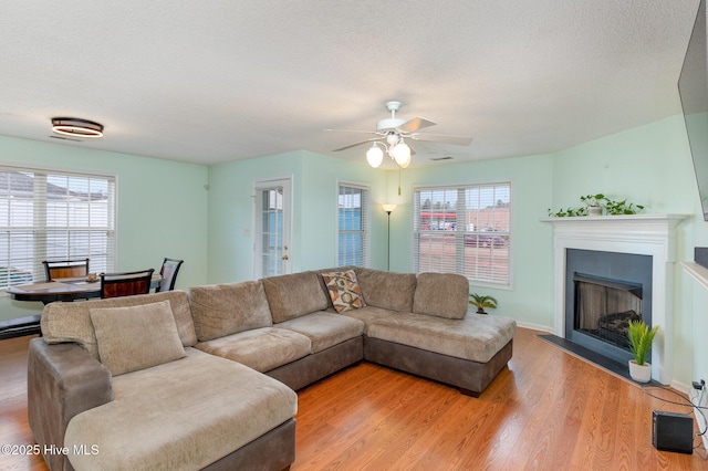 living room featuring a healthy amount of sunlight, ceiling fan, light hardwood / wood-style floors, and a textured ceiling