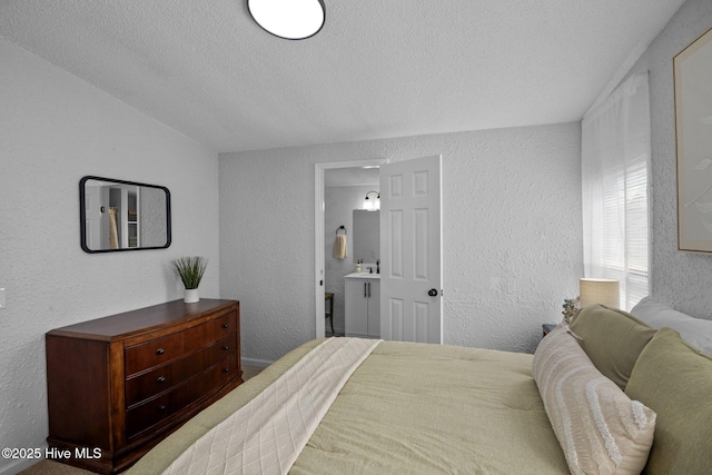 bedroom with connected bathroom, sink, and a textured ceiling