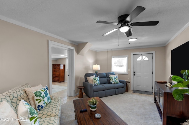 living room featuring a textured ceiling, ceiling fan, light colored carpet, and crown molding