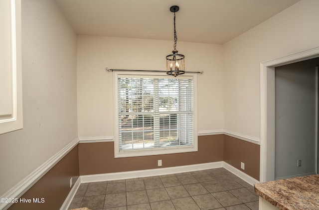 unfurnished dining area with dark tile patterned flooring and a notable chandelier