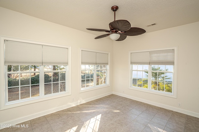 spare room featuring ceiling fan, light tile patterned floors, and a textured ceiling