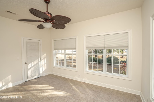 unfurnished room featuring ceiling fan, light tile patterned floors, and a textured ceiling