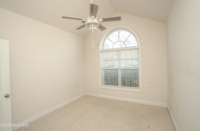 spare room featuring light carpet, vaulted ceiling, and ceiling fan