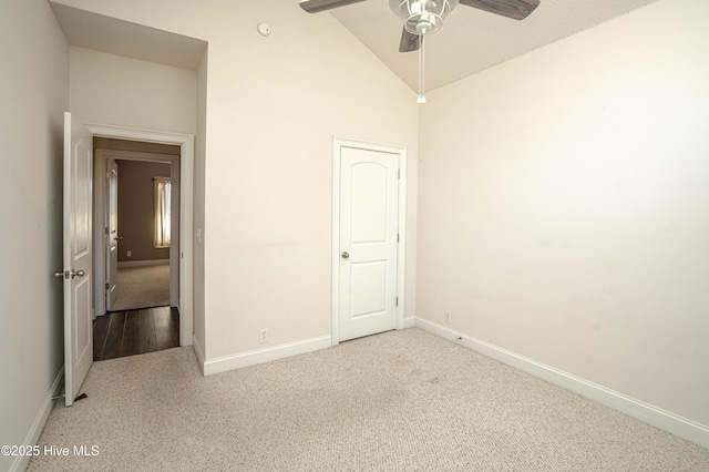 empty room featuring ceiling fan, high vaulted ceiling, and light colored carpet