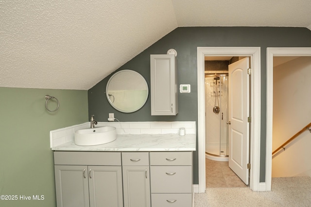 bathroom featuring vanity, a shower with door, lofted ceiling, tile patterned floors, and a textured ceiling