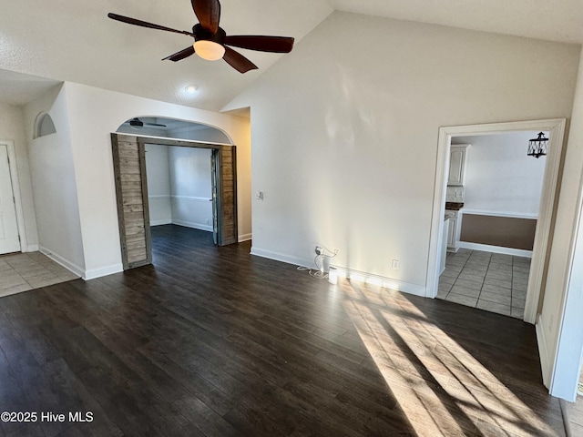 unfurnished living room featuring ceiling fan, dark hardwood / wood-style flooring, and vaulted ceiling